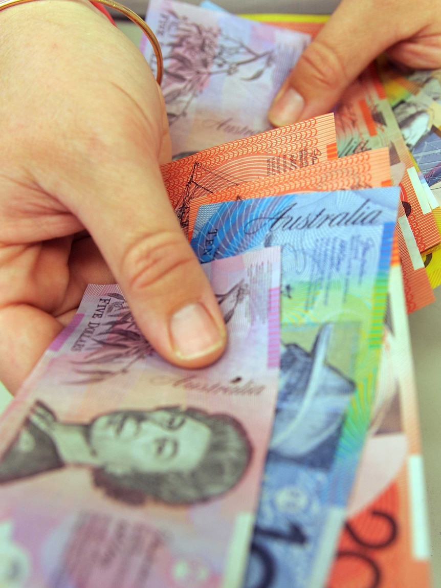Australian banknotes in a person's hand.