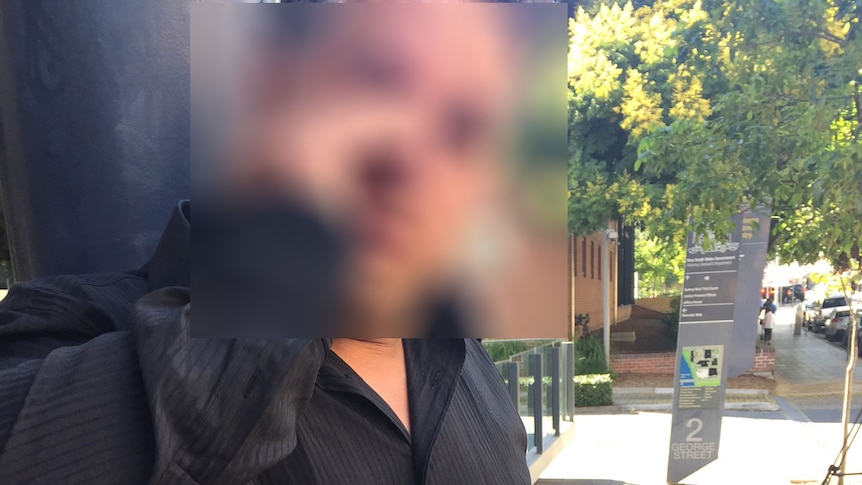 A man in a black shirt wiping away tears while talking to the media outside court.