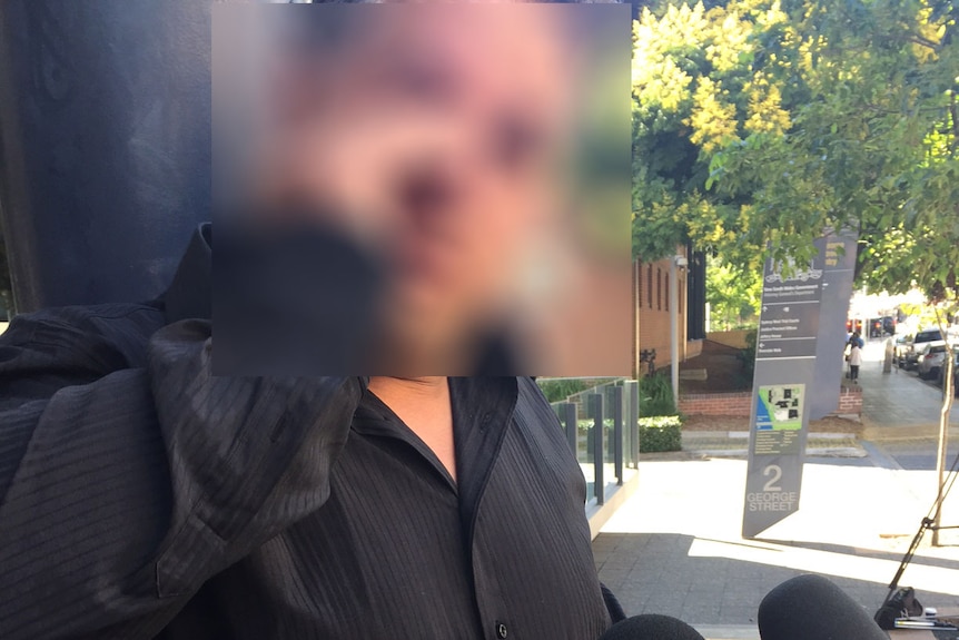 A man in a black shirt wiping away tears while talking to the media outside court.