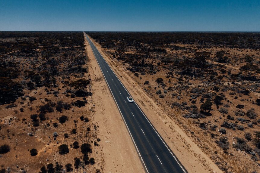 A lone car on an outback highway. 