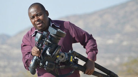 Producer Dingani Masuku carrying a tripod while on assignment in Africa.