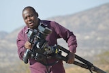 Producer Dingani Masuku carrying a tripod while on assignment in Africa.