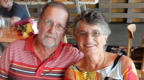 Older man and wife sitting side by side at a cafe, smiling