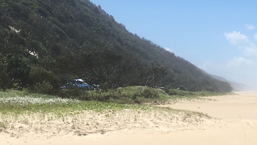 Large green hill on left with beach and hills in distance.