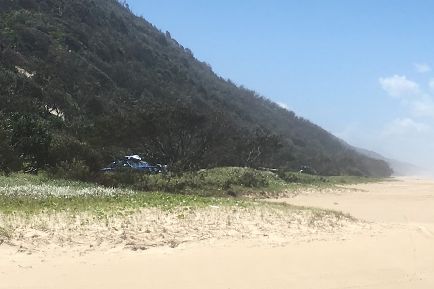 Large green hill on left with beach and hills in distance.