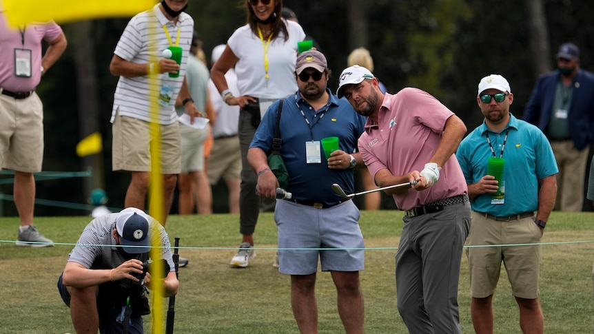 A golfer stares towards the flag as he hits a chip shot toward the green on day one at the Masters.