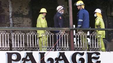 Police officers inspect the top floor verandah of the Palace Backpackers Hostel after the fatal fire