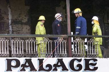 Police officers inspect the top floor verandah of the Palace Backpackers Hostel after the fatal fire