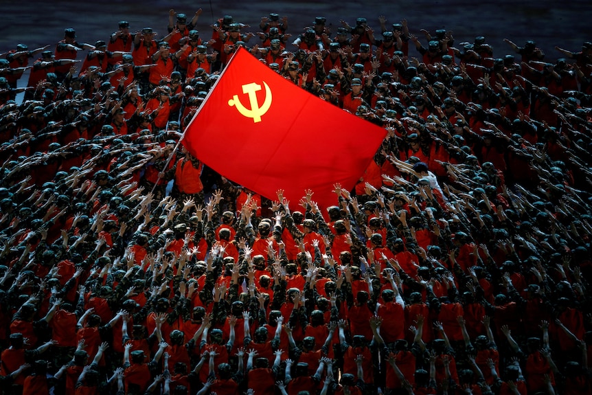 在2021年纪念中国共产党成立100周年的演出中，表演者们聚集在红旗周围。