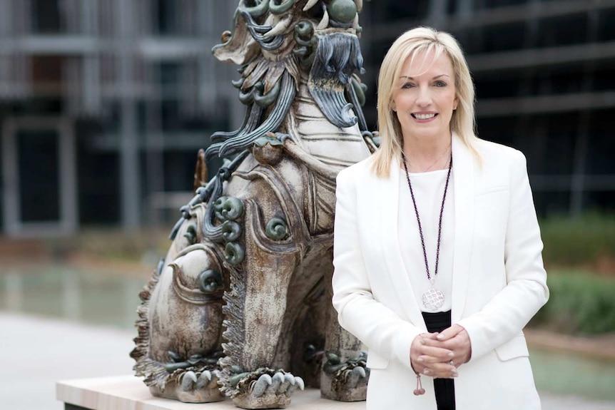 Christine stands in front of a dragon statue