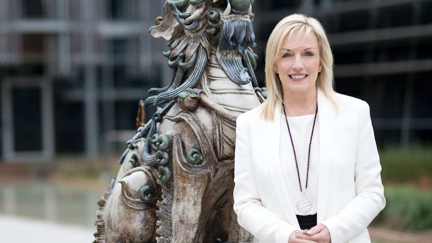 Christine Holgate stands in front of a dragon statue