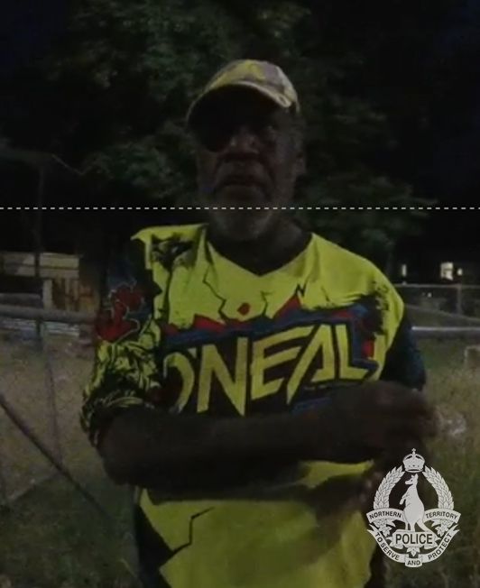 A dark low-res image of an Aboriginal man, wearing a bright yellow shirt and yellow cap.