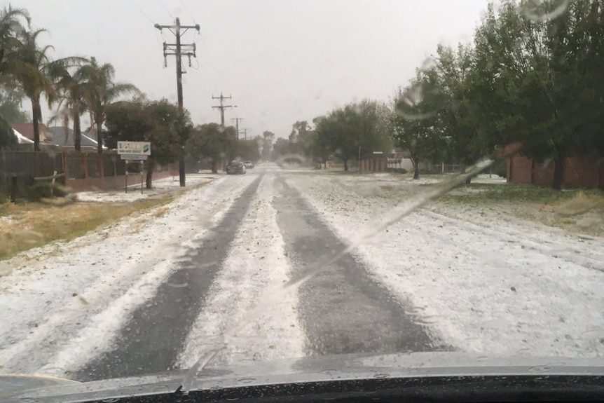 A road with hail that almost looks like snow across it.