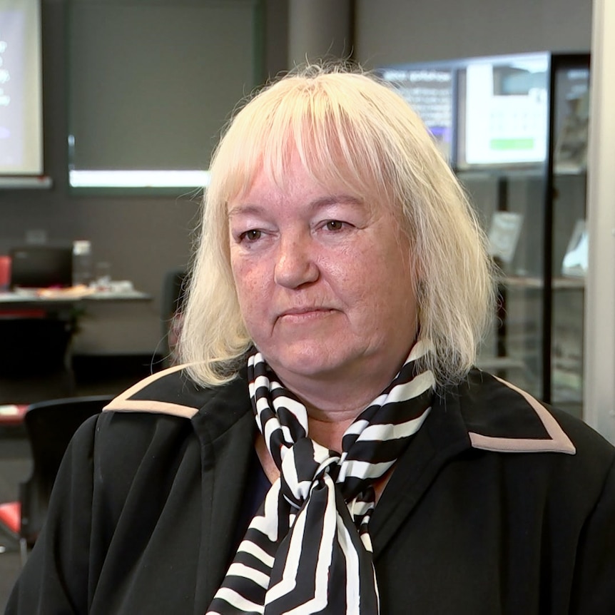 A women with white hair wearing black jacket and stripey scarf. 