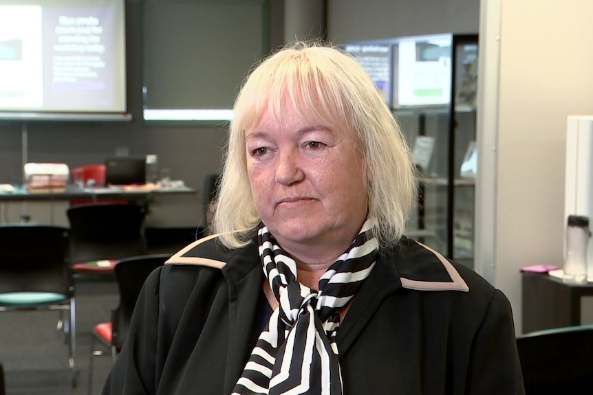 A women with white hair wearing black jacket and stripey scarf. 