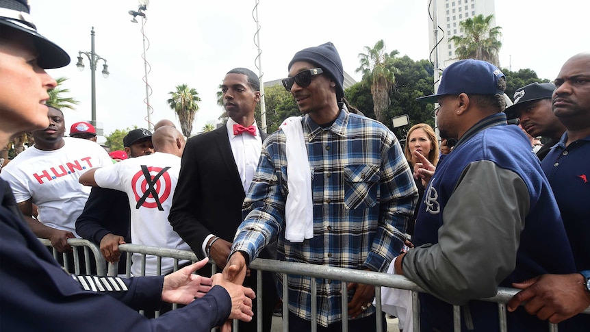 Rapper Snoop Dogg is greeted by a police officer
