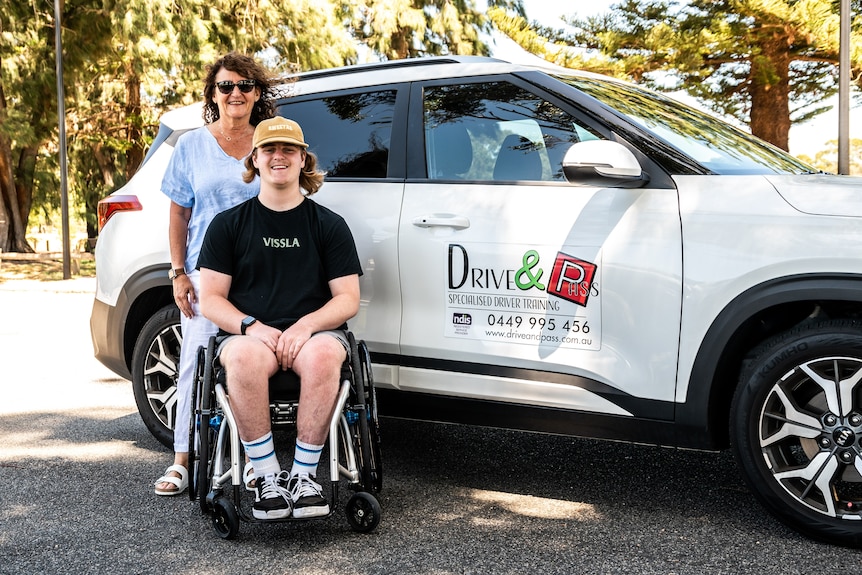 Max Devery in his wheelchair outside the car, with and Ro Anne Steele standing behind him.