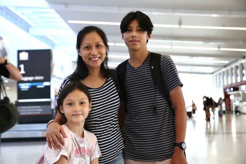 Catherine stands with her arms around her daughter and son.