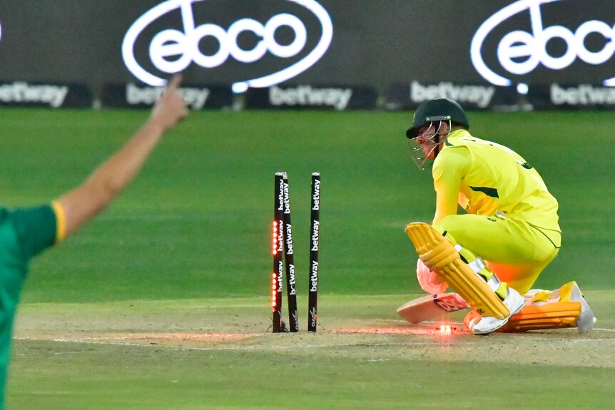 David Warner crouches down without a shoe