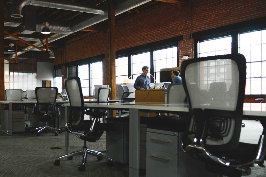 Chairs and desks set up in an open plan layout in a converted warehouse.