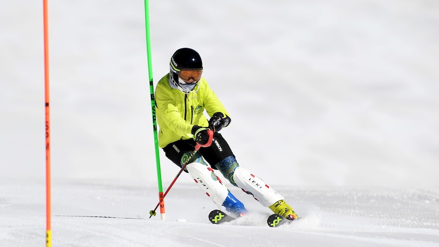 Rae Anderson is wearing a bright yellow jacket, and is skiing down a hill.