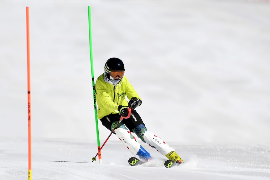 Rae Anderson is wearing a bright yellow jacket, and is skiing down a hill.