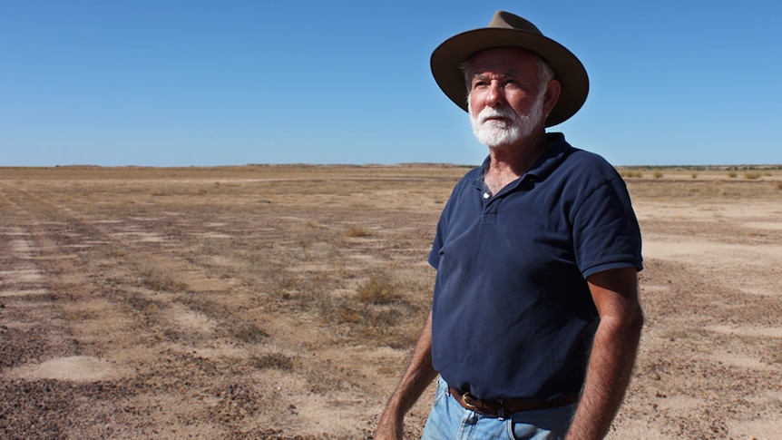 Ian Andrews in a cowboy hat, standing in a dry claypan located 140 kilometres east of Birdsville.