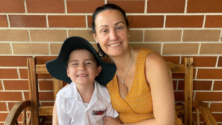 a woman sitting down smiling and holding her son