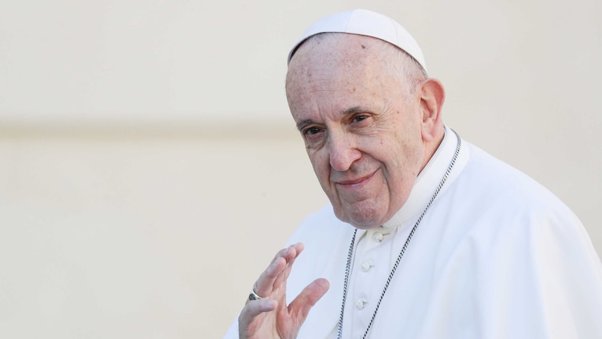 Pope Francis smiles and waves.