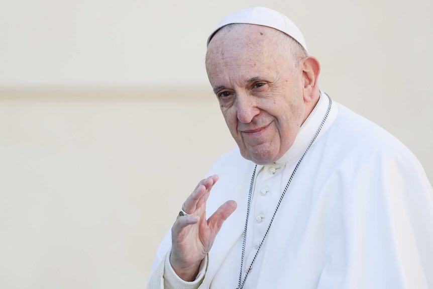 Pope Francis smiles and waves.