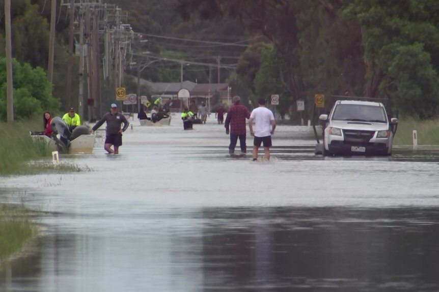 People walk down a flooded street near Rochester.