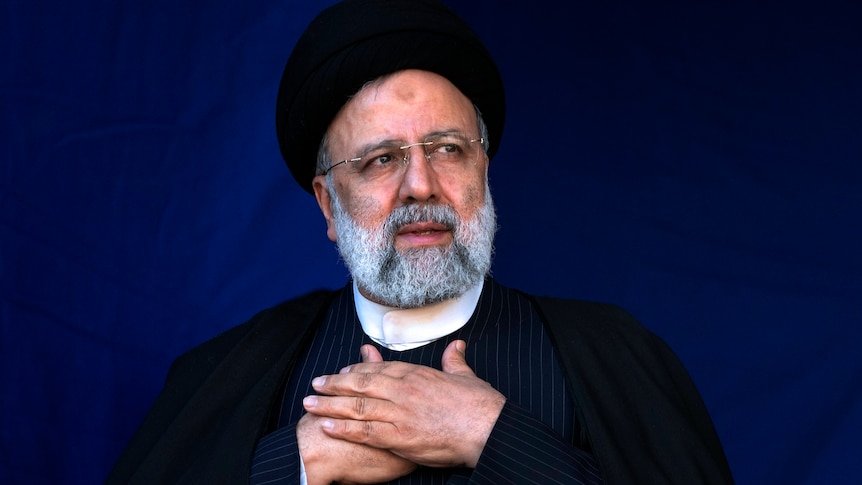 Iranian President Ebrahim Raisi clasping his hands over his chest