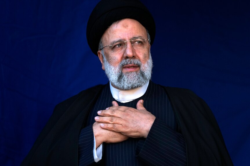 Iranian President Ebrahim Raisi clasping his hands over his chest