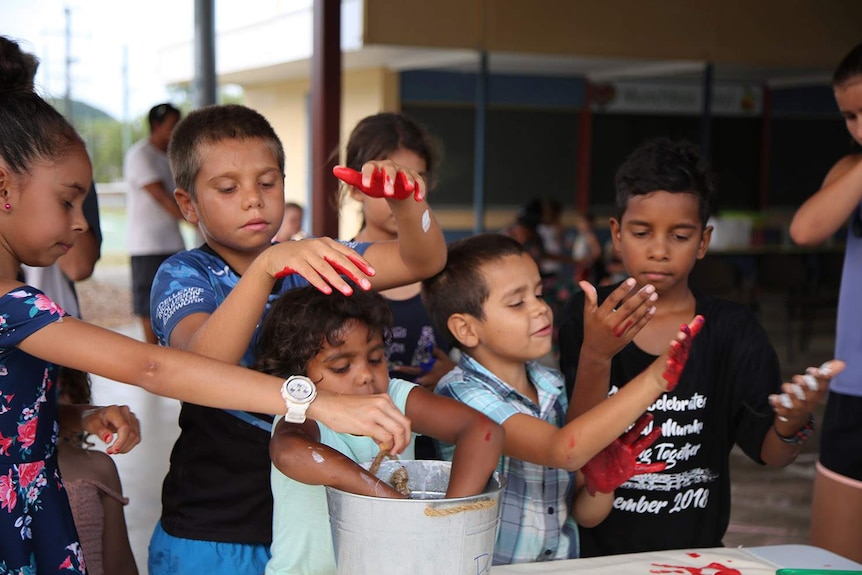 Students work with red paint in a bucket during a class at Mossman State School in far north Queensland in December 2018