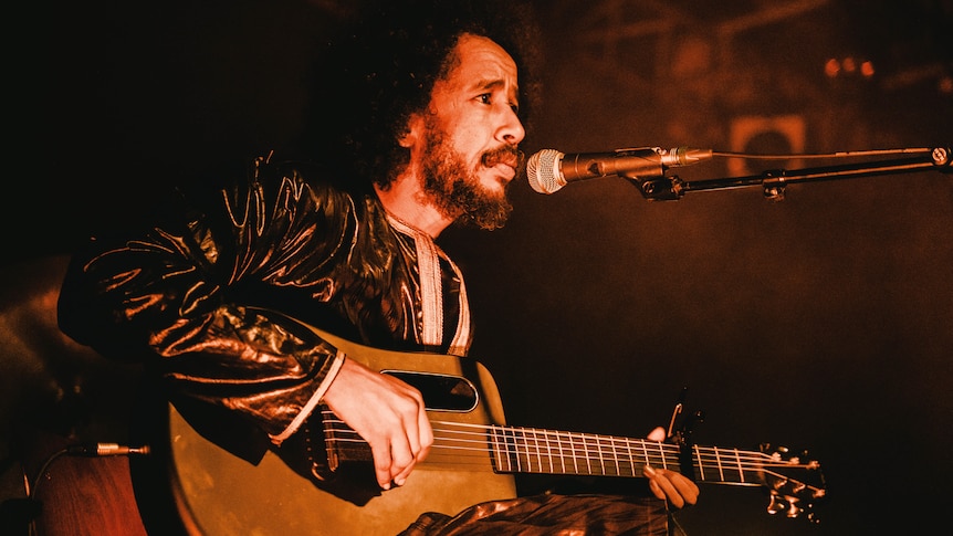 Ousmane Ag Mossa from Tamikrest holding a guitar on stage