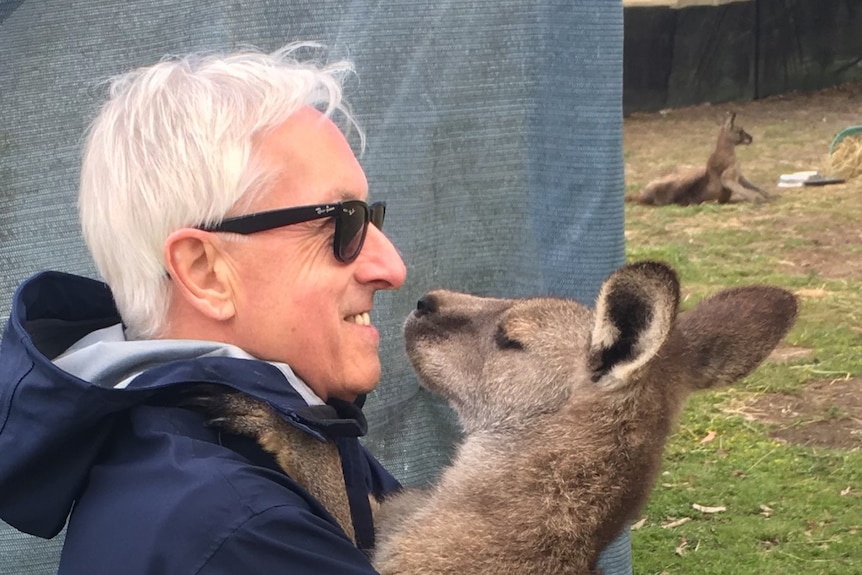 Wildlife carer Ian Slattery hugging a grown kangaroo