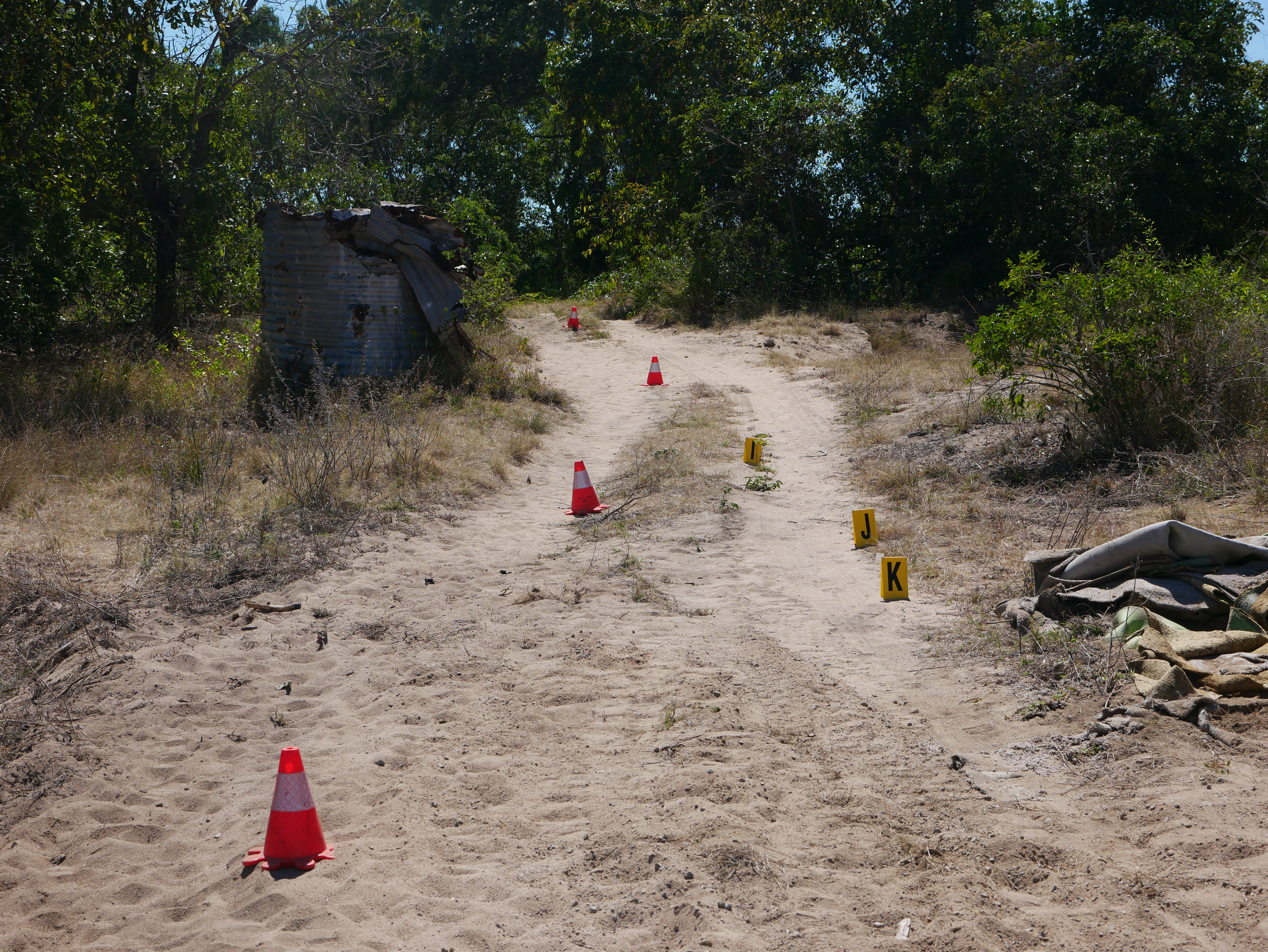Witches hats line a sandy path at the crime scene
