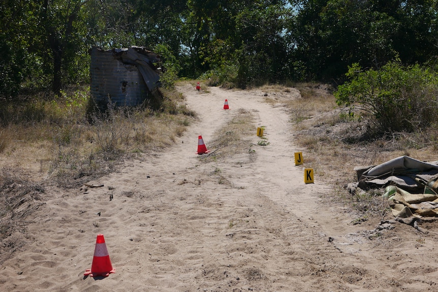 Witches hats line a sandy path at the crime scene