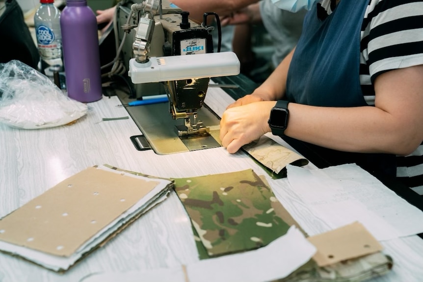 a piece of army khaki fabric lays next to a sewing machine