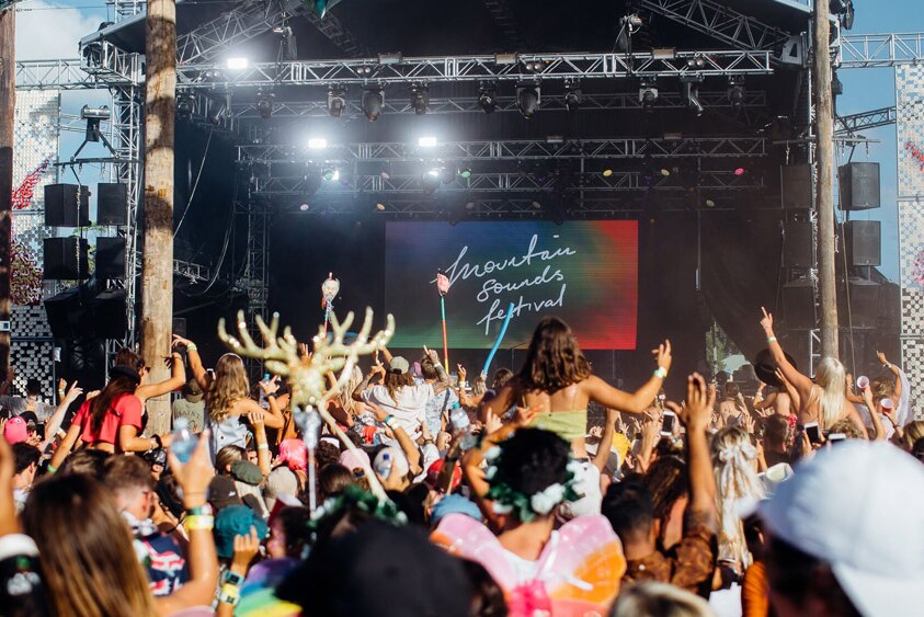 An image of a crowd in front of a stage at an outdoor music festival.
