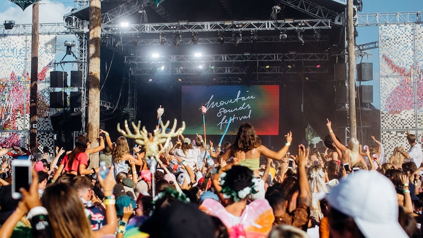 An image of a crowd in front of a stage at an outdoor music festival.