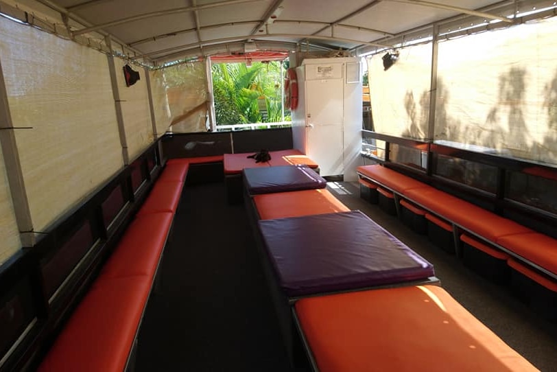 An image of a fishing charter boat with canvas sides. The seats are new, orange and purple vinyl.