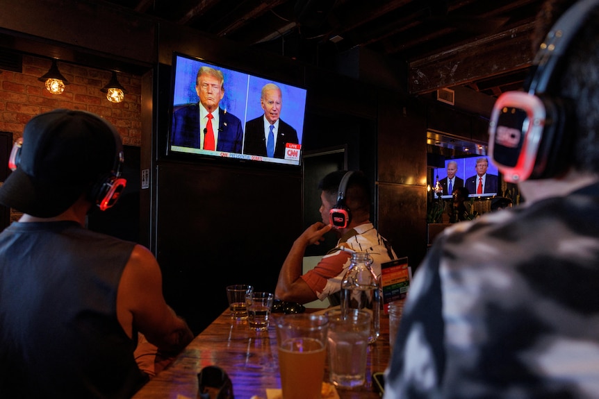 People watch the debate with earphones on in a pub 