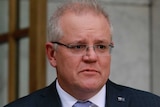 Scott Morrison stands at a lectern in a courtyard with an Australian flag behind him