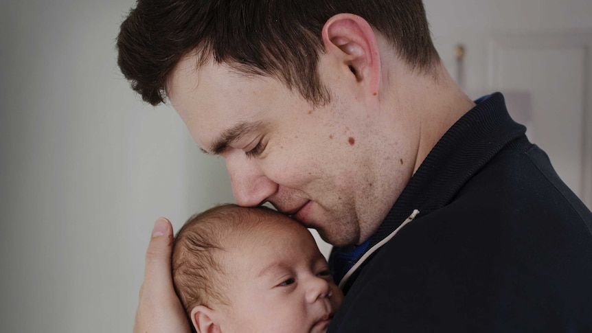 Father Ross Yabsley kissing his child.