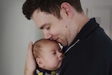 Father Ross Yabsley kissing his child.