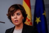 Soraya Saenz de Santamaria speaks at a press briefing in front of EU and Spain flags
