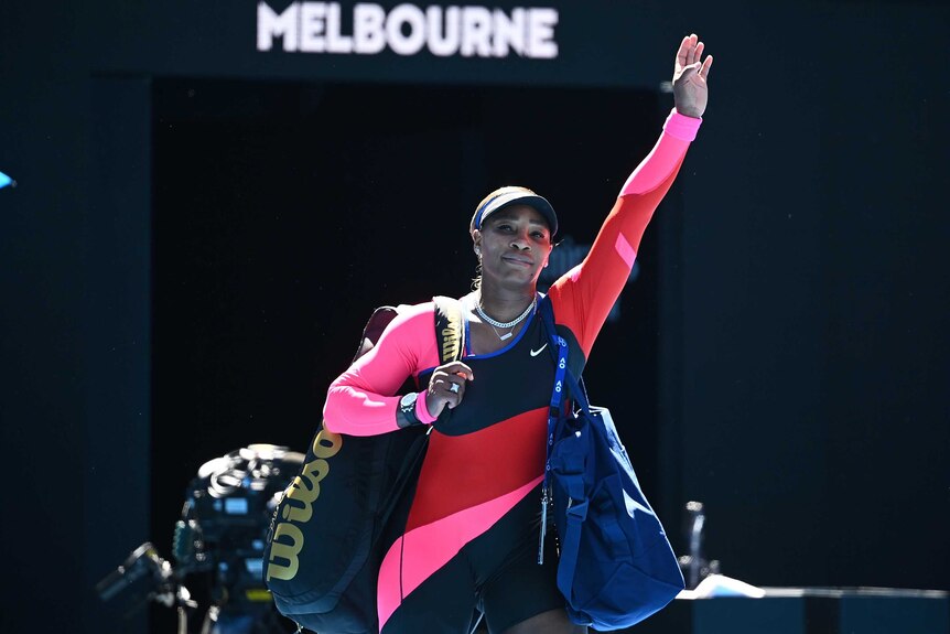 A tennis player looks up at the stands and raises her hand in salute to the crowd after a loss.