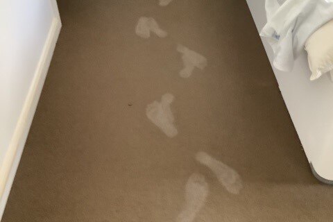 Footprints track through brown mud down a hallway.