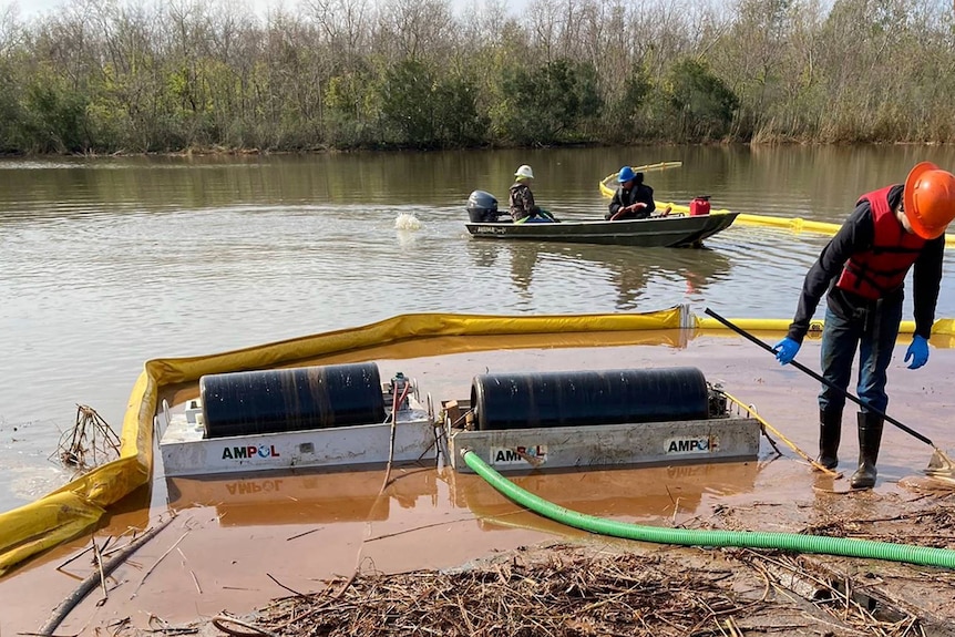 Workers conduct a cleanup operation in a river. 